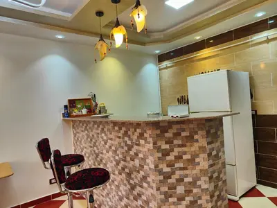 a kitchen with a bar with two chairs and a refrigerator at 2bedroom apartment in Summer Land Beach Resort in Hurghada