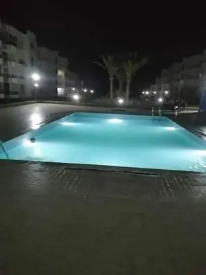 a large blue swimming pool at night with at 2bedroom apartment in Summer Land Beach Resort in Hurghada