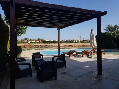 a pavilion with chairs and an umbrella next to a pool at Gorgeous Villa in Gouna with Heated Private Pool in Hurghada