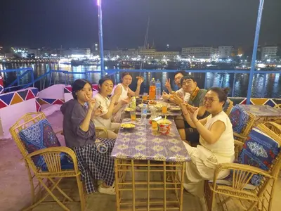 a group of people sitting around a table on a deck at Mostafa Jamaica guesthouse in Aswan