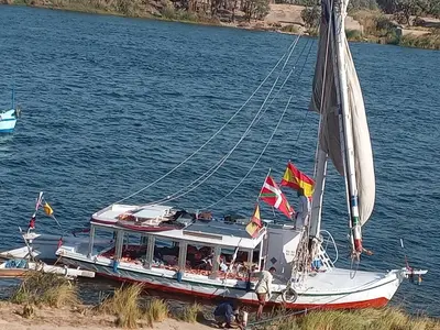a boat on the water with flags on it at Noby Guest House in Luxor