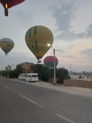 two hot air balloons flying over a road at Noby Guest House in Luxor