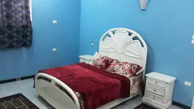 a blue bedroom with a bed with a red blanket at Bob Marley Guest House in Luxor