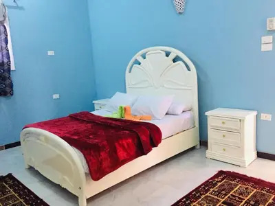 a bedroom with a white bed and a blue wall at Bob Marley Guest House in Luxor