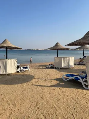 a beach with chairs and umbrellas and the ocean at Apartment with private Beach in Sahl Hasheesh in Hurghada
