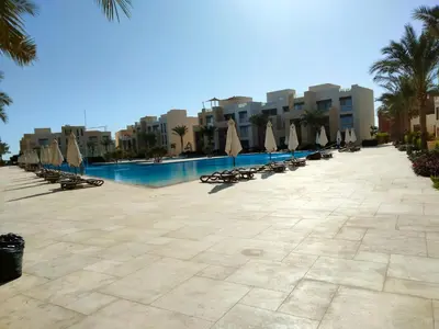 a swimming pool with chairs and umbrellas in a resort at Mangrovy 2 BR Gouna in Hurghada