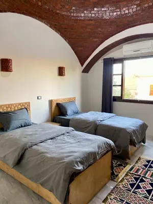 two beds in a room with a large window at Tasneem Palace in Luxor