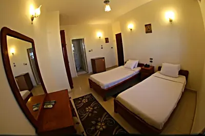 a hotel room with two beds and a mirror at Luxor Hotel Hurghada in Hurghada