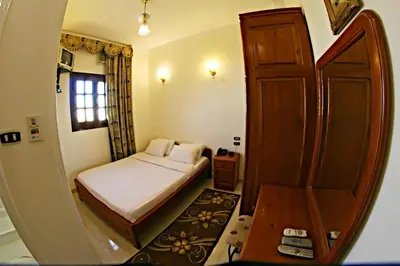 a small bedroom with a bed and a wooden door at Luxor Hotel Hurghada in Hurghada