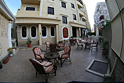 a patio with tables and chairs in front of a building at Luxor Hotel Hurghada in Hurghada