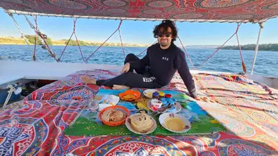 a man sitting on a table with food on a boat at My Dream Nile Felucca in Aswan