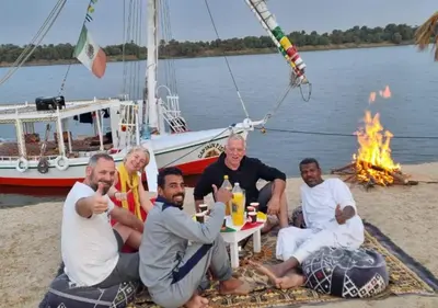 a group of men sitting around a table with a fire at My Dream Nile Felucca in Aswan