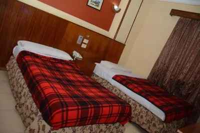 a hotel room with two beds and a plaid blanket at New Saint Catherine Hotel in Luxor