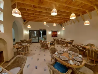 a restaurant with wooden tables and chairs and a fireplace at Benben by Dhara Hotels - Adults Only in Aswan