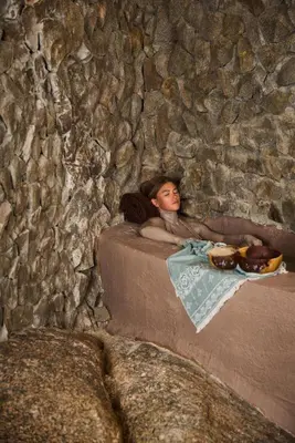 a young girl laying on a bed in a stone wall at Benben by Dhara Hotels - Adults Only in Aswan