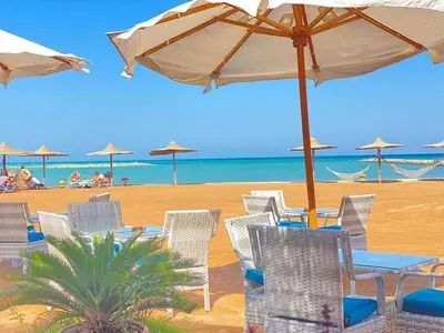 a group of chairs and tables with umbrellas on a beach at Tertels beach resort hurghada F 2-6 in Hurghada