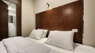 a bed with white pillows and a wooden headboard at Sphinx Luxor Apartment in Luxor