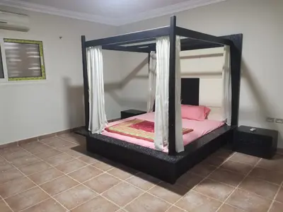 a bedroom with a black bed with pink sheets at Marvel flat in Hurghada