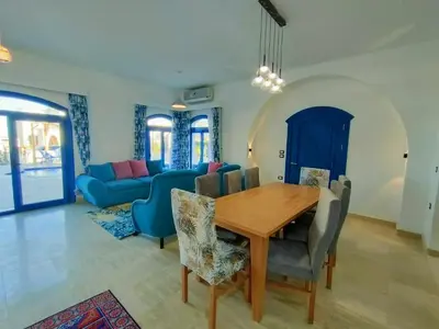 a dining room with a wooden table and a blue couch at Amaros Sahl Hasheesh sea view Villa with Pool سهل حشيش in Hurghada