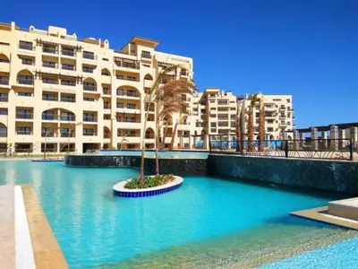 a building with a palm tree in the middle of a pool at AlDAU Heights Modern Brand New Apartments in Hurghada