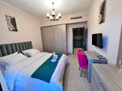 a bedroom with a bed and a table and a tv at AlDAU Heights Modern Brand New Apartments in Hurghada