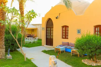 a yellow house with a dog sitting in the yard at Sekhmet Retreat Centre in Luxor