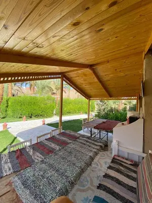 a pavilion with a wooden roof with rugs on a patio at Sekhmet Retreat Centre in Luxor