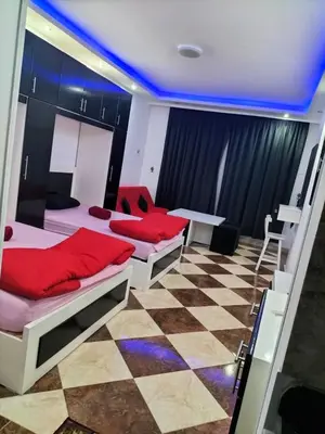 a room with two beds and a table in it at 304 الشيراتون بلازا in Hurghada