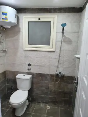 a bathroom with a toilet and a television on the wall at 304 الشيراتون بلازا in Hurghada