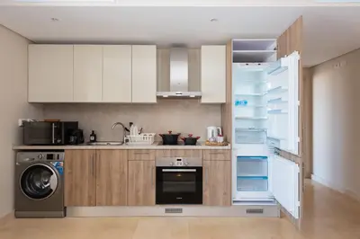 a kitchen with white cabinets and a washer and dryer at Chilled & Serene 1BDR Mangroovy Pool & Sea View in Hurghada
