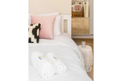 a white bed with two rolled up towels on it at Chilled & Serene 1BDR Mangroovy Pool & Sea View in Hurghada