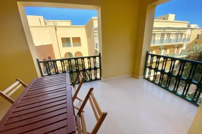 a balcony with a wooden table and chairs on it at Minimal & Central 1BDR Apt Abu Tig Marina in Hurghada