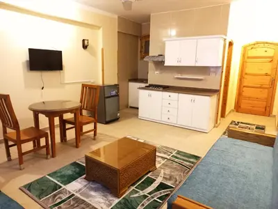 a living room with a table and a kitchen at Embrace Guest House in Luxor