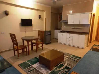 a living room with a table and a kitchen at Embrace Guest House in Luxor
