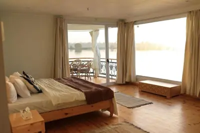 a bedroom with a bed and a balcony at Embrace 1 Nile Sailing Dahabiya in Luxor
