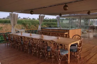 a long wooden table and chairs on a deck at Embrace 1 Nile Sailing Dahabiya in Luxor
