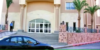 a car parked in front of a building with palm trees at JWE Residence - Quality experience near Red Sea in Hurghada