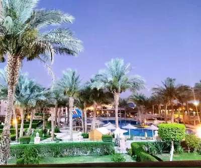 a resort with palm trees and a pool at night at JWE Residence - Quality experience near Red Sea in Hurghada