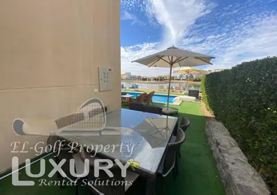 a glass table with an umbrella next to a pool at Tawila Villa T1-15 in Hurghada