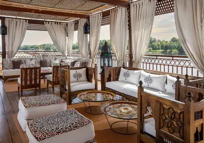 a room with couches and tables on a balcony at Dahabeya Molouky Nile Cruise- Every Monday from Luxor- Aswan for 05 nights in Luxor