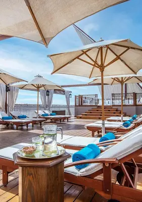 a deck with tables and umbrellas on the beach at Dahabeya Molouky Nile Cruise- Every Monday from Luxor- Aswan for 05 nights in Luxor