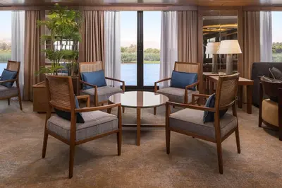a living room with chairs and a table and windows at Jaz Elite Regent Nile Cruise - Every Monday from Luxor for 07 & 04 Nights - Every Friday From Aswan for 03 Nights in Luxor