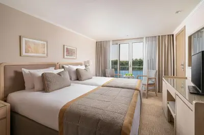 a hotel room with a large bed and a television at Jaz Elite Regent Nile Cruise - Every Monday from Luxor for 07 & 04 Nights - Every Friday From Aswan for 03 Nights in Luxor