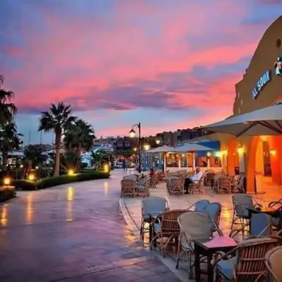 a patio with tables and chairs at sunset at new marina heart of Hurghada in Hurghada