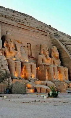 a large rock wall with statues on it at One Love Guesthouse & Restaurant in Luxor