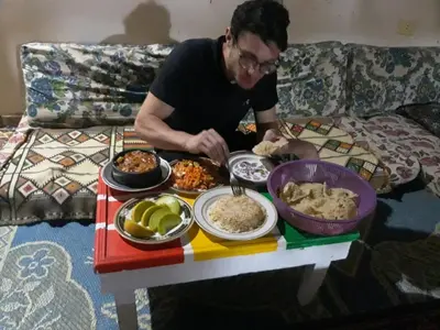 a man sitting on a couch with a table full of food at One Love Guesthouse & Restaurant in Luxor
