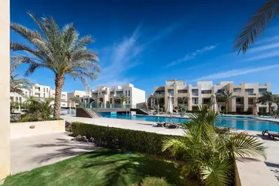 a view of the resort with a swimming pool and palm trees at Jazzy 1BDR w Outdoor Pool View Terrace Free Pool & Beach Access in Hurghada