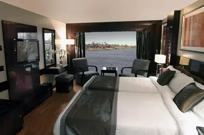 a bedroom with a large bed and a view of the water at Le Fayan Nile Cruise - Every Monday from Luxor for 4 & 7 Nights, and every Friday from Aswan for 3 & 7 Nights in Luxor