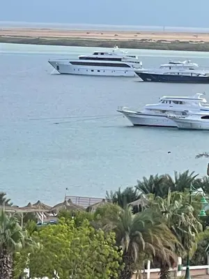 three boats in a body of water with palm trees at Cozy Apartment in Qadd el-Barûd