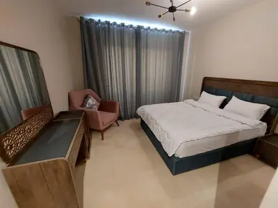 a bedroom with a large bed and a chair at MCJ Luxury 2 Bedrooms Apartment in Hurghada